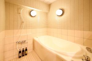 a bathroom with a tub and a sink and two lights at Hotel Dio (Adult Only) in Osaka