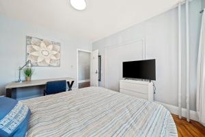 a bedroom with a bed and a desk and a tv at Cozy Up in 5BR Apt Near Charming Oak Square in Boston