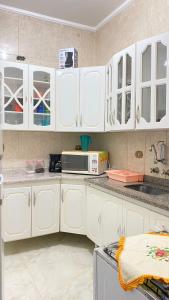 cocina con armarios blancos y microondas en Apartamento conforto e requinte!, en São Paulo