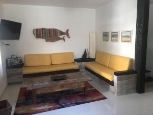 - un salon avec deux canapés jaunes et une table basse dans l'établissement Casa em Cond Geriba 400mt Praia com Espaço Gourmet, à Búzios