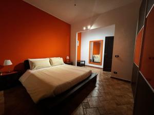 una camera con un grande letto con una parete arancione di OPUNTIA DELL'ETNA BIKE HOUSE a Mascalucia