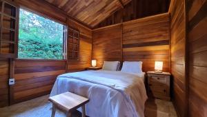 a bedroom with a bed in a wooden cabin at Chalé Arado 313 in Monte Verde