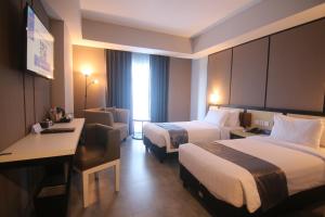 a hotel room with two beds and a desk at BeSS Mansion Hotel Surabaya in Wonocolo