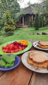 una mesa de madera con platos de fruta. en Tegal Jero Homestay, en Jatiluwih