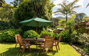 a table and chairs with a green umbrella at Aotea Lodge Great Barrier in Tryphena
