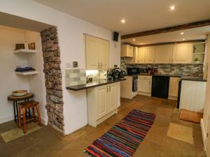 eine Küche mit weißen Schränken und einer Steinmauer in der Unterkunft Bay Leaf Cottage in Kirkby Stephen