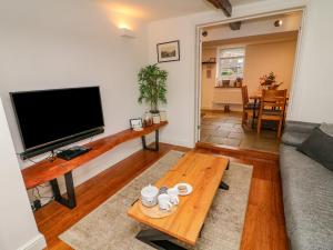 a living room with a flat screen tv and a coffee table at Bay Leaf Cottage in Kirkby Stephen