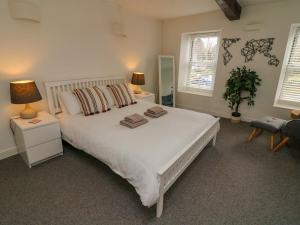 a bedroom with a large white bed and two windows at Bay Leaf Cottage in Kirkby Stephen