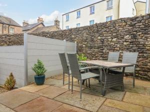 a table and chairs on a patio with a stone wall at Bay Leaf Cottage in Kirkby Stephen
