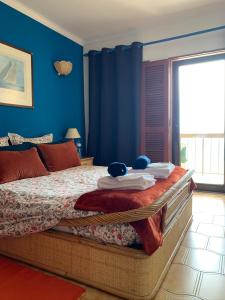 Un dormitorio con una cama con paredes azules y una ventana en Casa vista Azul, en Sesimbra