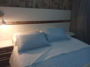 Cama blanca con almohadas azules y cabecero en charmoso apto Centro de Curitiba, en Curitiba