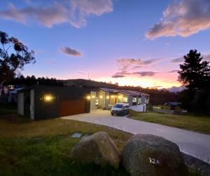 un coche aparcado frente a un garaje al atardecer en Jindabyne House 1, Modern 3 bedroom home, alpine views & fireplace en Jindabyne