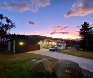 a car parked in front of a garage at sunset at Jindabyne House 1, Modern 3 bedroom home, alpine views & fireplace in Jindabyne