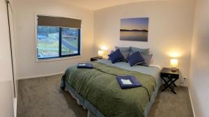 a bedroom with a large bed and a window at Jindabyne House 1, Modern 3 bedroom home, alpine views & fireplace in Jindabyne