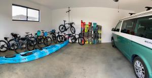 a garage with bikes and a kayak and a van at Jindabyne House 1, Modern 3 bedroom home, alpine views & fireplace in Jindabyne