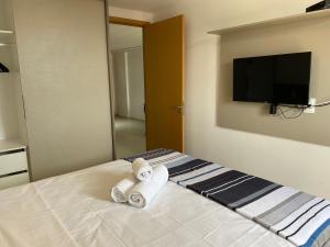 1 dormitorio con toallas en una cama y TV de pantalla plana en Bela Hospedagem - EcoSummer Cobertura em Tambaú, en João Pessoa