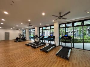 une salle de sport avec une rangée de tapis roulants et des fenêtres dans l'établissement Casa Sepuluh @ Core Soho Suites Kota Warisan, à Sepang