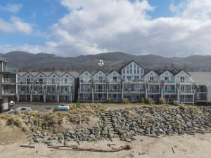 a row of houses on a beach with mountains in the background at Rockaway beach vibes,Waterfront Oceanfront Rockaway Beach House near Downtown,WIFI, Washer Dryer in Rockaway Beach