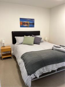 ワナカにあるCentral Wanaka Apartmentのベッドルーム1室(大型ベッド1台、黒いヘッドボード付)