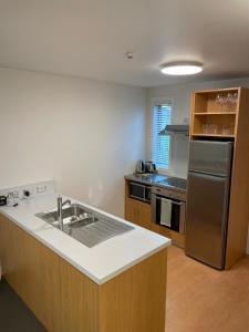 ワナカにあるCentral Wanaka Apartmentのキッチン(シンク、ステンレス製の冷蔵庫付) +3枚の写真