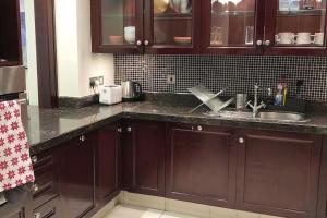 uma cozinha com armários castanhos escuros e um lavatório em 2 Bedroom Old Town Garden Apartment - The 108 Residences em Dubai