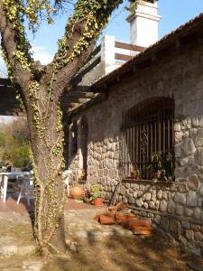 un edificio de piedra con un árbol delante de él en Casa Soleares en Villa Las Rosas