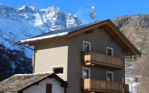 un edificio con balconi e montagne innevate di B&B Le Fió a Valtournenche