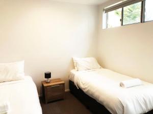 two twin beds in a room with a window at 3 Bedroom Central Beachside Kingscliff Apartment with Pool in Kingscliff +17 photos