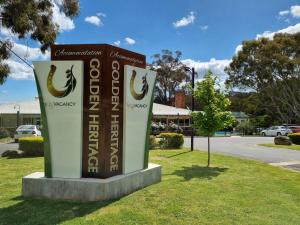 un cartel en el césped junto a una calle en Golden Heritage Accommodation, en Beechworth