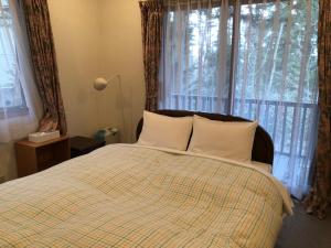 a bedroom with a bed with white pillows and a window at Cottage 62 Seseraginomori Kyu-karuizawa in Karuizawa