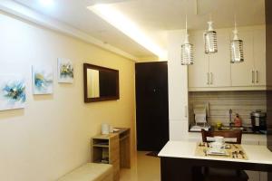 a kitchen with white cabinets and a table and chairs at Italian Inspired Tropical-Themed Studio Condo in Davao City