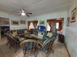 a living room with a couch and chairs and a tv at Matumi Self Catering in Marloth Park