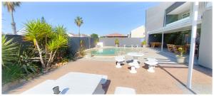 a backyard with a swimming pool and a house at Beachwood Inn Melkbosstrand in Cape Town