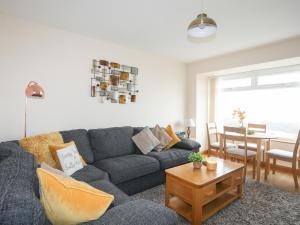 uma sala de estar com um sofá cinzento e uma mesa em Sandy Toes em Rhosneigr