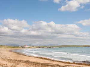 una spiaggia con persone in acqua e un edificio di Sandy Toes a Rhosneigr