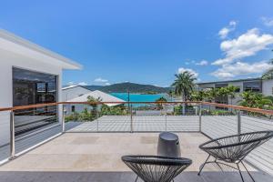 a balcony with two chairs and a view of the ocean at Whitsunday living on Hillcrest in Airlie Beach