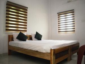 1 Schlafzimmer mit einem Bett mit weißer Bettwäsche und 2 Fenstern in der Unterkunft Hotel Padma Shree , Madurai - Near Airport in Madurai