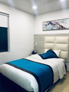 a bedroom with a large bed with a blue blanket at Hotel San Antonio Guarne in Guarne