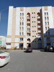 Квартиры Уют в Туркестане في Türkistan: مبنى كبير فيه سيارات تقف امامه