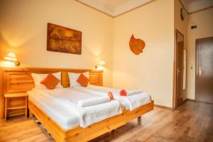 ブダペストにあるManzard Panzioのベッドルーム1室(白いシーツが備わる木製ベッド1台付)