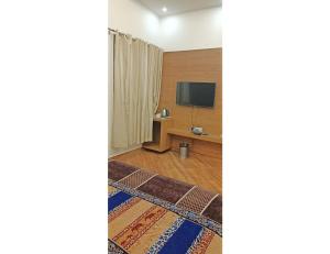 a room with a tv and a bed and a rug at Royal Comfort Cottage, Panipat in Pānīpat