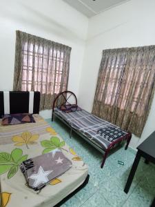 a bedroom with two beds and two windows at Homestay Che Wan in Kuantan
