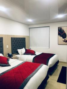 a hotel room with two beds and a screen at Hotel San Antonio Guarne in Guarne