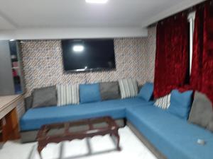 uma sala de estar com um sofá azul e uma televisão em Villa 1299 em Plage de Mehdia