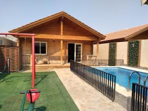 a house with a swimming pool with a putting green at شاليهات الكوخ السويسري وأكوابارك in Ash Shishah