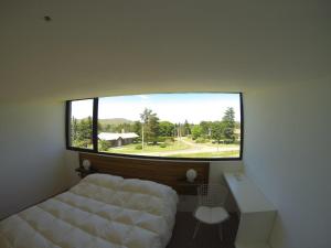 a bedroom with a bed and a large window at Hoyo 6 Rincón del Golf in Sierra de la Ventana