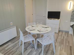 mesa blanca con sillas y TV en una habitación en VITTEL LOC'S - Le 215 Classé 4 étoiles, Spacieux et calme, en Vittel