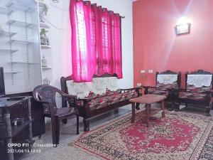 Habitación con sillas, mesa y paredes rosas. en Coorg villas apartment stay en Madikeri