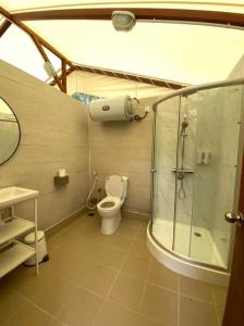 uma casa de banho com um WC e uma cabina de duche em vidro. em Canopy Villa Nuang Hill em Bentong