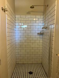 een wit betegelde douche met een zwart-witte tegelvloer bij Onse Rus Guesthouse in Prince Albert